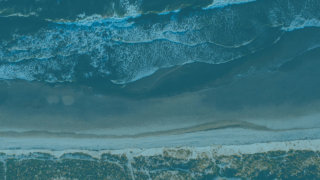 The background image shows from above ocean waves crashing onto a beach.